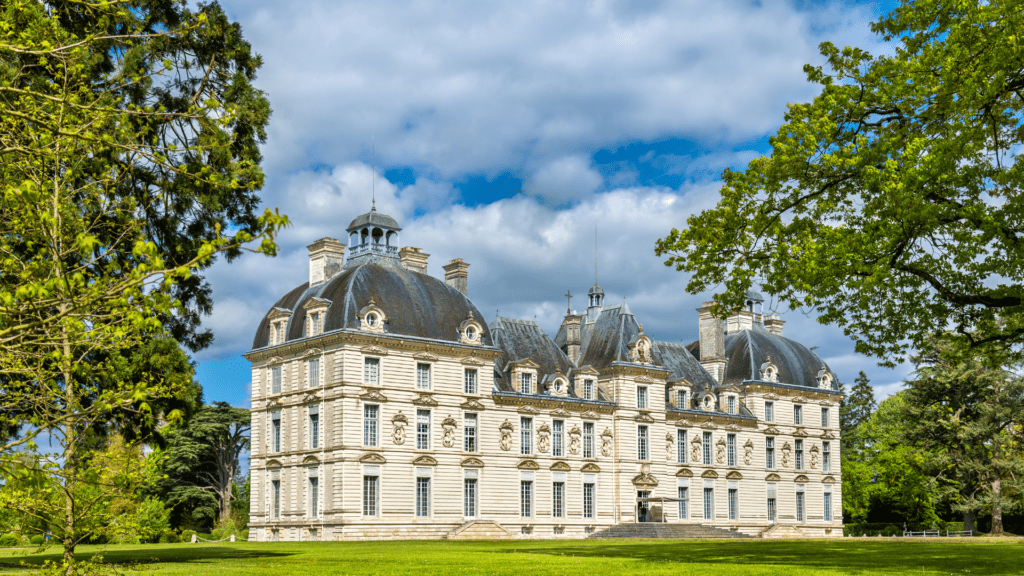 Chateau de Cheverny is a short day trip from Paris - photo is of the exterior of the 3 story home surrounded by trees and lush Loire Valley landscape. 