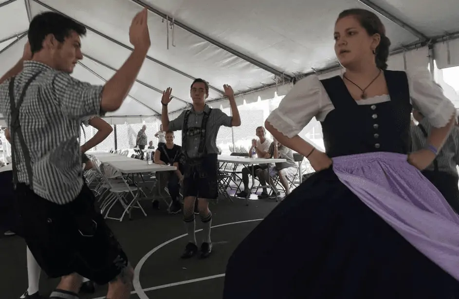Photo Credit: IRB Ocktoberfest.  Photo shows three young adults dressed in german attire dancing at the IRB Oktoberfest.