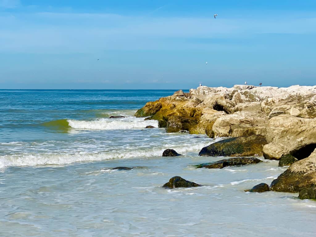 upham beach st pete fl with seagulls and pelicans flying in the distance near the rock jetty.  