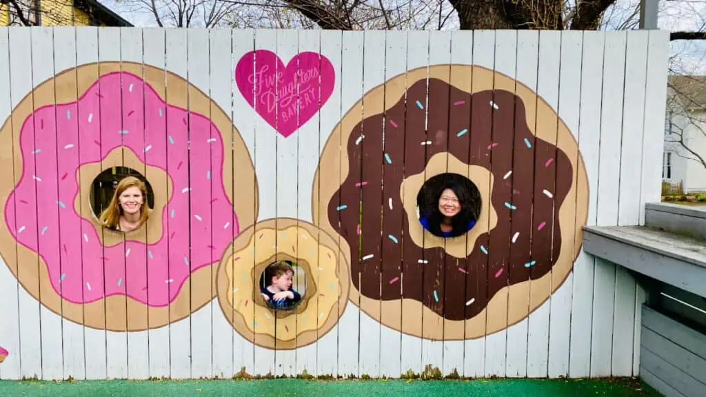 Erin at Five Daughters Bakery showing her and family each with their head in a donut mural