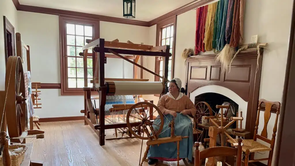 woman in Colonial Williamsburg sewing in period piece clothing
