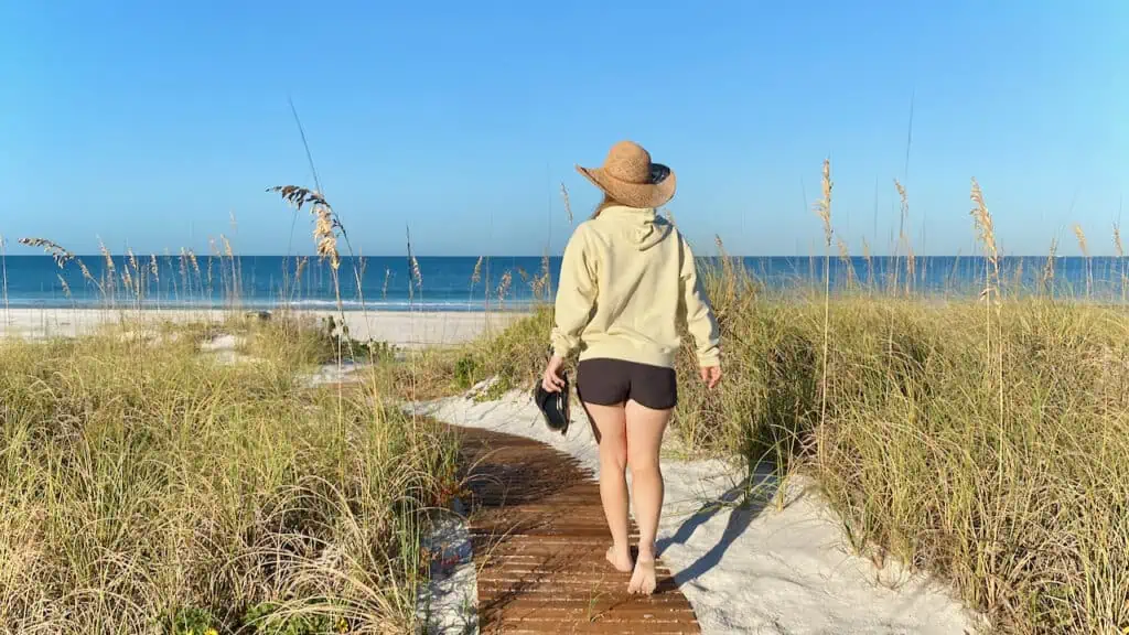 Erin walking in St Pete Beach along the sand dunes and water.